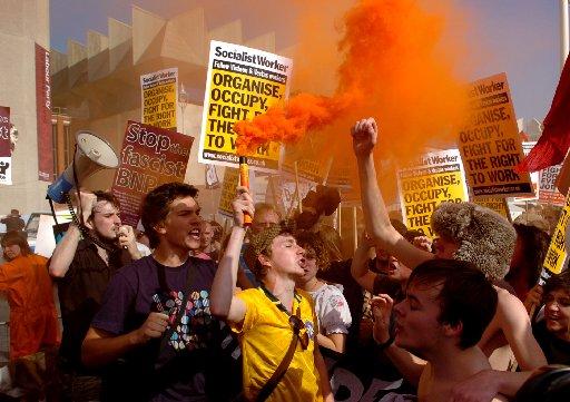 Orange smoke fills the air as flares were let off during the Anti Government protest outside the Labour Party Conference in Brighton today .