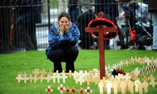 Donna Varney lays a small cross for her husband's best friend who was in the Royal Marines when killed