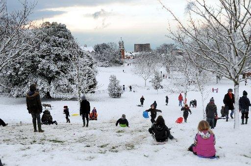 Looking like a scene from a Lowry painting families enjoy sledging in Queens Park Brighton this morning