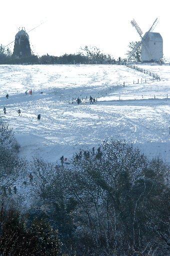 Snow scene as people take advantage of the festive weather on Clayton Hill by Jack and Jill windmills