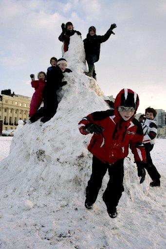 Children pictured playing in the snow on Hove Lawns, Ben, 11, in red is sliding down a giant snow slide.