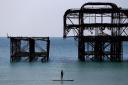 A man enjoys the warm weather as he paddle board's past the West Pier.  Picture: Gareth Fuller/PA Wire.