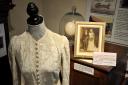 Pictue shows the wedding dress made by Cynthia Chase for her wedding to Francis Price. Picture in background shows their wedding day, 5th August 1939, in background.  From Boots to Bustles exhibition at Queens hall, High Street, Cuckfield..