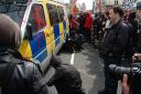 DAMAGE: A protester lets air out of the tyres of a police van which has been scrawled with graffifi