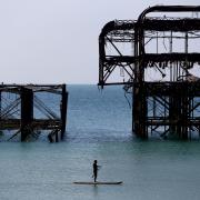 A man enjoys the warm weather as he paddle board's past the West Pier.  Picture: Gareth Fuller/PA Wire.