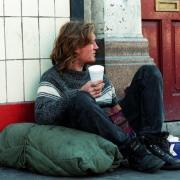 A homeless man asks passers-by for change