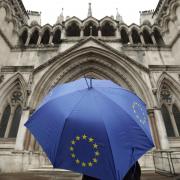 A person under an umbrella carrying the EU flag outside the High Court in London.  Picture: Yui Mok/PA Wire