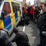 DAMAGE: A protester lets air out of the tyres of a police van which has been scrawled with graffifi