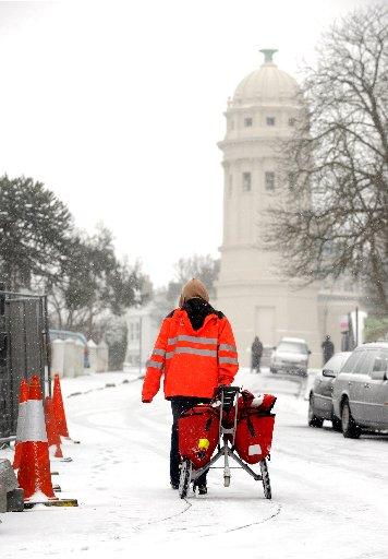 A postman battles through the snow in the Queens Park area of Brighton this morning
