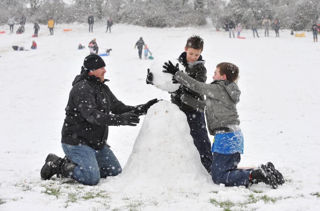 Dad Darren Stoneham with sons Louie and Zak build a snowman.
