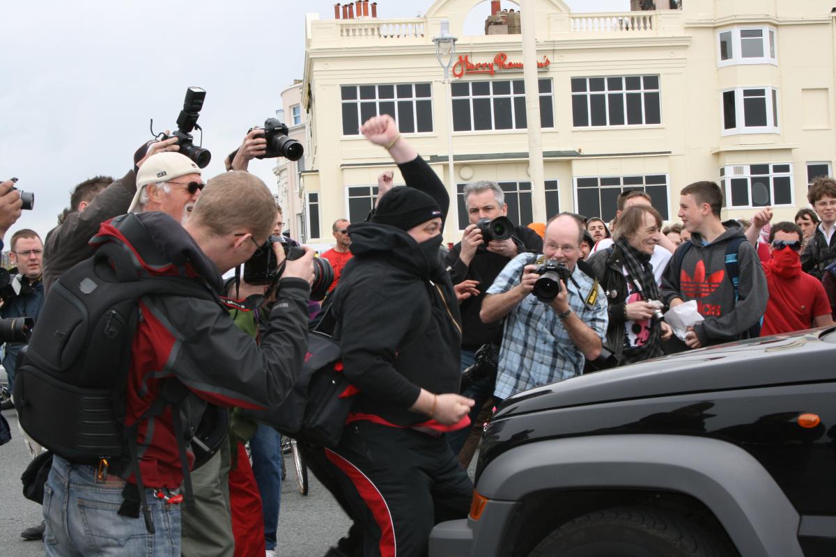 A protester attacks a car outside Harry Ramsden's on the seafront. Our photographer Simon Dack can been seen in the background (wearing a blue check shirt). Picture by Ben Collier.
