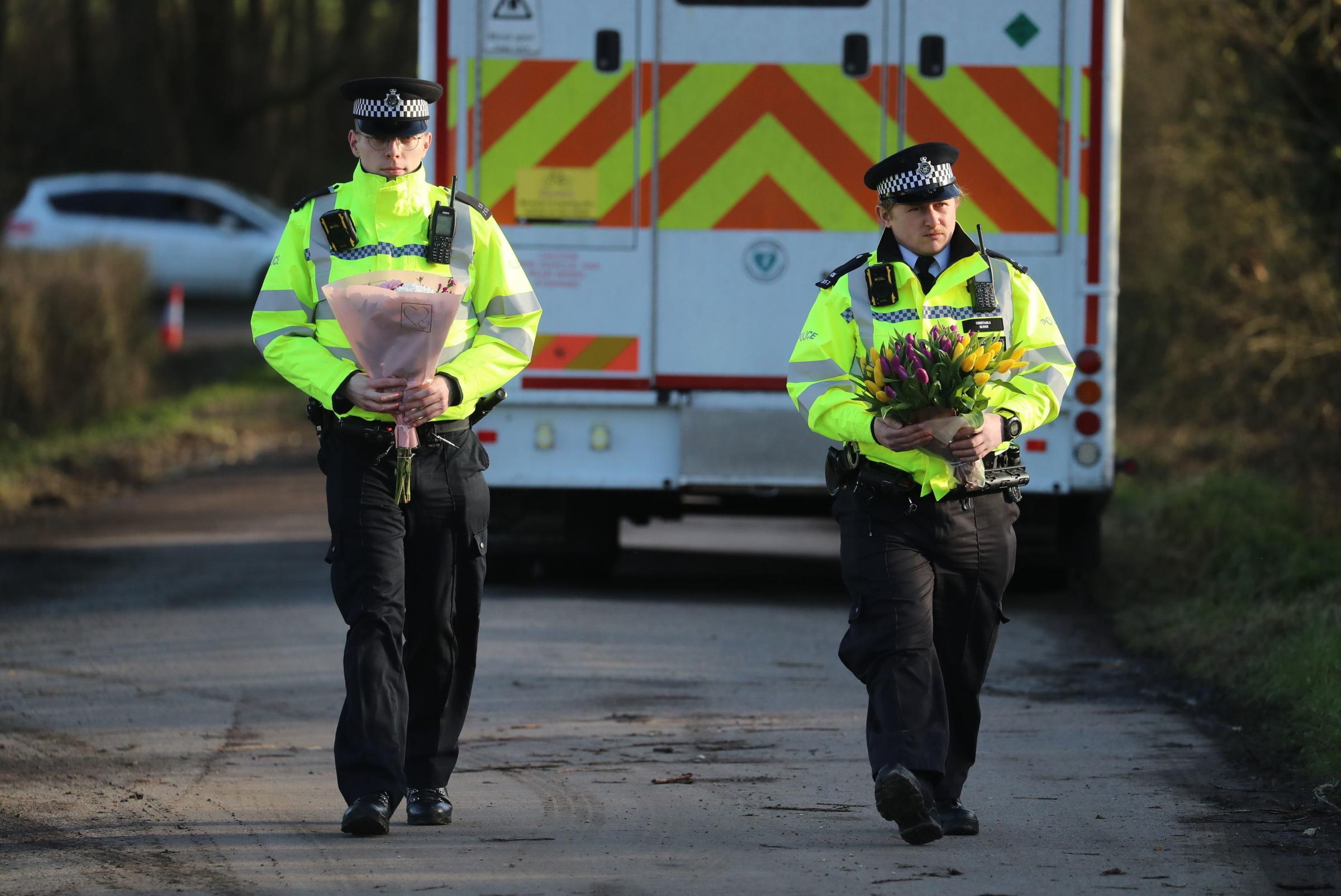 Police officers carry flowers brought by members of the public to the entrance of Great Chart Golf and Leisure in Ashford in Kent, after detectives confirmed that human remains found nearby are those of missing woman Sarah Everard. Picture date: Friday
