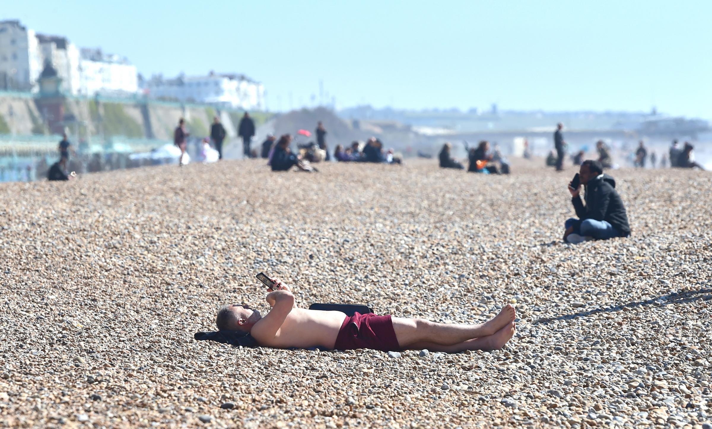 Brighton UK 29th March 2021 - A sunbather enjoys a lovely sunny day on Brighton beach as lockdown restrictions have started to ease in England Temperatures are expected to reach the mid 20s in some parts of the South East over next few days. : Credit