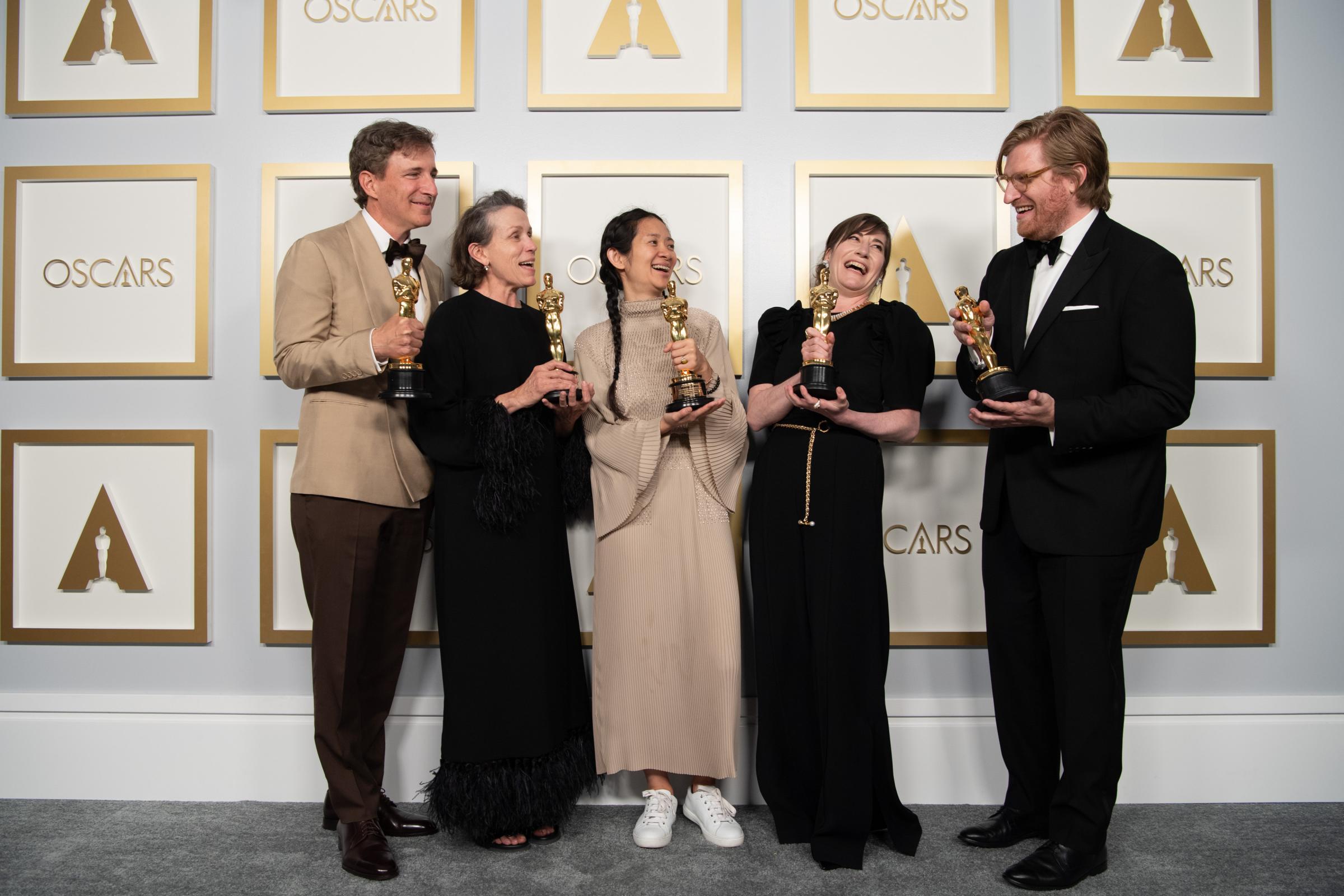 Peter Spears, Frances McDormand, Chloe Zhao, Mollye Asher, and Dan Janvey, holding their Oscar statues after winning best picture for the film Nomadland