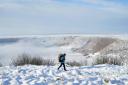 A person walks through snow above the Hole of Horcum at the North York Moors National Park (Danny Lawson/PA)
