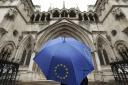 A person under an umbrella carrying the EU flag outside the High Court in London.  Picture: Yui Mok/PA Wire