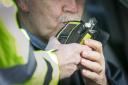 A driver blows into a police breathalyser during a random drink driving checkpoint