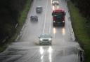 Vehicles driving through service water on a flooded part of the A37 near Bristol (Ben Birchall/PA)