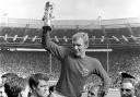 England captain Bobby Moore holding the World Cup aloft as he is carried by his teammates