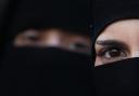 Two women wearing Islamic niqab veils stand outside the French Embassy during a demonstration