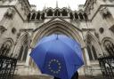 A person under an umbrella carrying the EU flag outside the High Court in London, as three judges have ruled against the Prime Minister's decision to trigger Article 50 of the Lisbon Treaty of the Lisbon Treaty and start the UK's exit from the