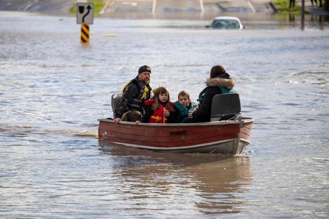 People who were stranded by high water due to flooding are rescued by a volunteer operating a boat in Abbotsford, British Columbia
