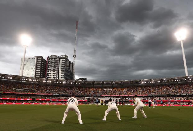 The Argus: England players warm up between innings as storm clouds gather during day one of the first Ashes test at The Gabba, Brisbane.