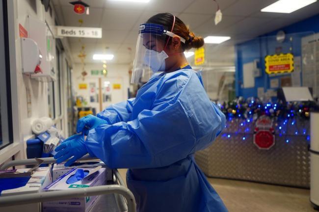 A nurse puts on PPE on a ward for Covid-19 patients: credit - Victoria Jones/PA
