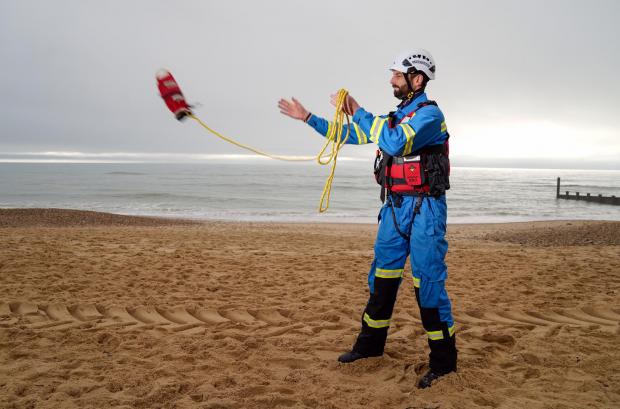 The Argus: HM Coastguard Coastal Operations Area Commander Tom Wright casts a throwline on Southbourne beach in Dorset (PA)