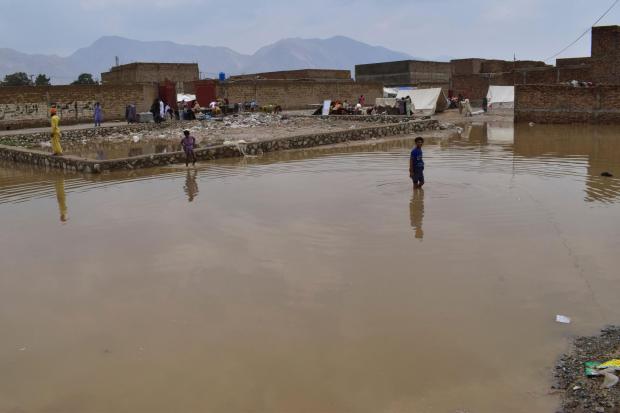 Boys wade through a flooded area on the outskirts of Quetta, Pakistan