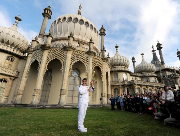 The Argus: Zachary Narvacz with the Olympic torch outside of the Royal Pavilion in Brighton: credit - Simon Dack