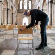 Senior Verger Luke Marshall cleans socially distanced chairs at Chichester Cathedral in West Sussex, as they prepare to reopen for public worship on 5th July, as further coronavirus lockdown restrictions are lifted in England. PA Photo. Picture date: