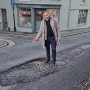 Councillor Kevin West pointing at the pothole