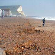 A man walks along a Sussex beach
