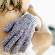 A woman scrubbing her back with loofa gloves
