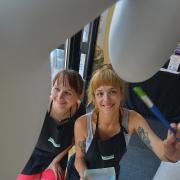Amy Lawrence (lt), Marketing Manager and Buyer for Lawrence Art Shop and local artist Aimee Brigginshaw (crct), painting the snowdog in store.  Picture: Susannah Binney