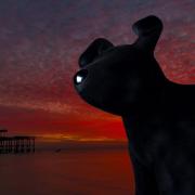 A Snowdog looms out over Brighton seafront at sunset.