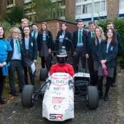 The teenagers from Oriel School and Seaford Head with the car that inspired them on a university visit