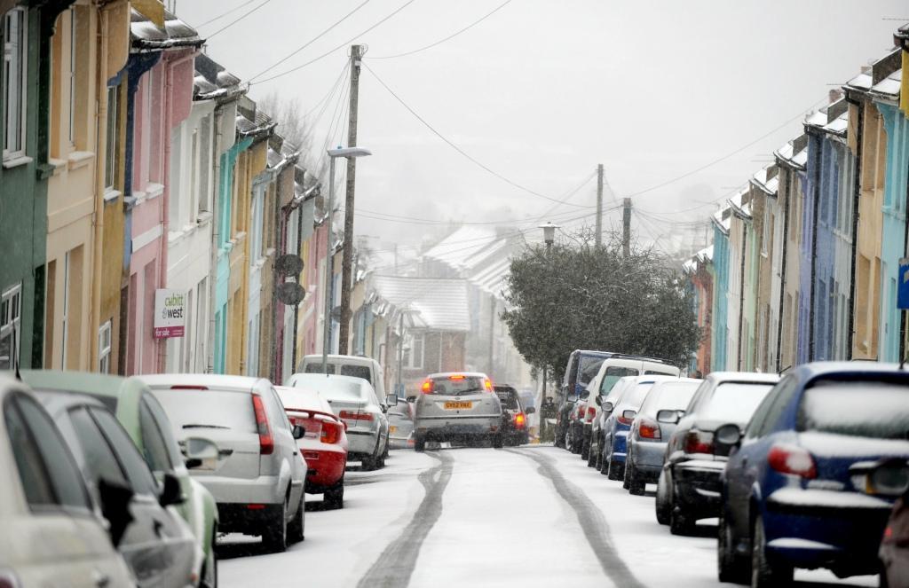 Cars carefully negotiate the steep hills of the Hanover area of Brighton as snow falls this morning

