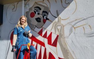 Ola Volo standing with her mural