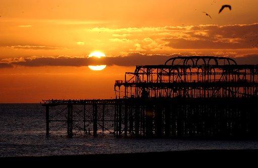 The framework of the ravaged pier with the sun setting in the background